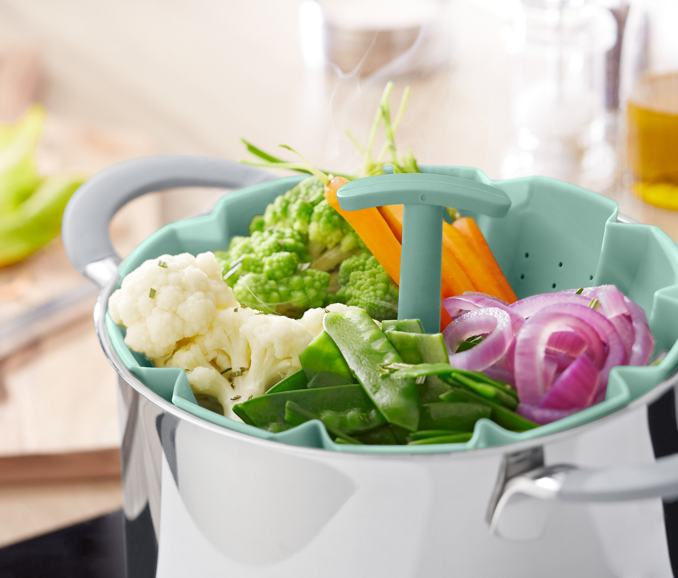 Zöldségek párolókosárban egy fazék felett.