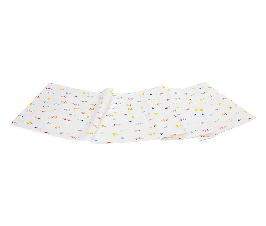 Egy fehér szövet apró, színes virágmintával, összehajtva egy fehér háttéren.