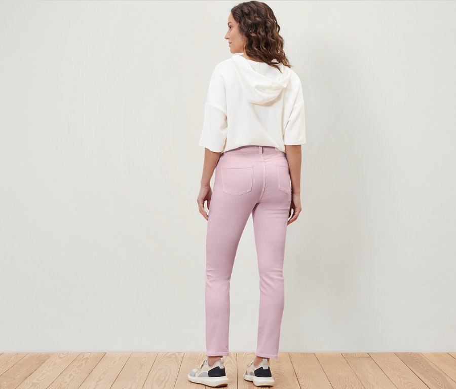 Egy nő háttal áll a kamerának, és színes farmernadrágot visel, »Emma« fazonban.