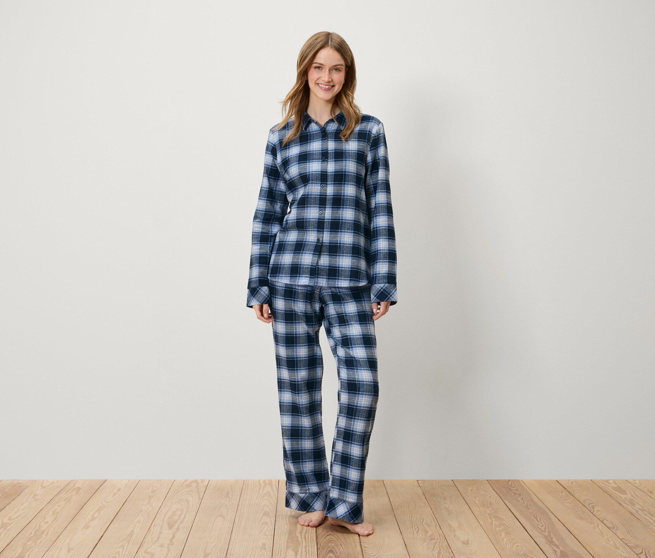 Egy nő áll kék kockás pizsamában.