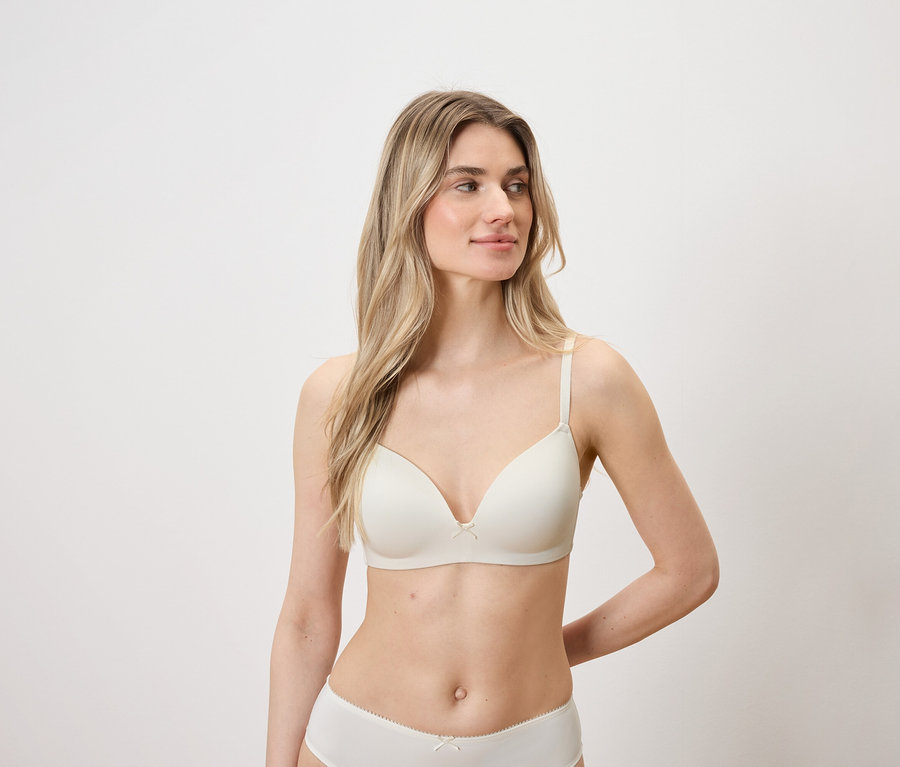 Szőke hajú, világos bőrű nő világos melltartót és bugyit visel.