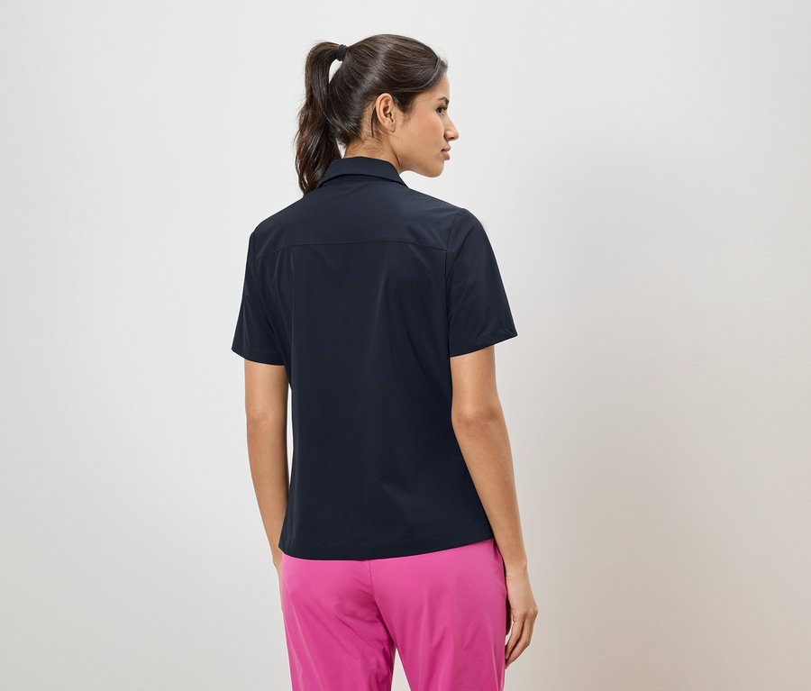 Hátulnézet egy lófarokos nőről, aki sötétkék inget és rózsaszín nadrágot visel.