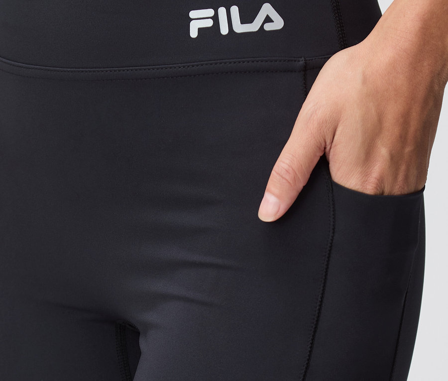Közeli kép fekete Fila leggingsről, zsebben kézzel.