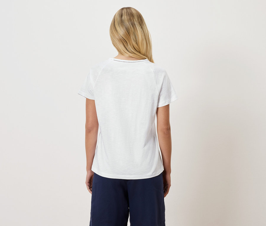 Hátulnézet egy szőke nő fehér pólóban és sötétkék nadrágban.