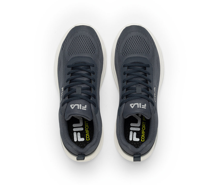 Egy pár sötétszürke Fila sneaker fehér talppal, felülről nézve. A cipők hálós felsőrésszel és fehér Fila logókkal rendelkeznek az oldalukon és a talpbetéteken, a talpbetéteken „COMFORT” felirattal.