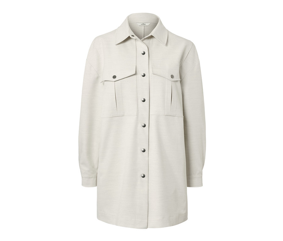 Egy krémszínű női lezser ing gallérral, zsebekkel és ezüst patentokkal.