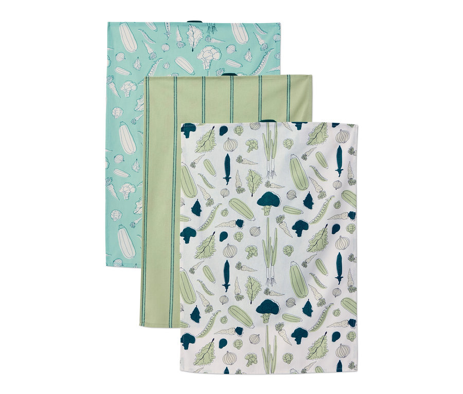 Három konyharuha különböző mintákkal. Egy világoskék zöldségekkel, egy zöld csíkos és egy fehér zöldségekkel.