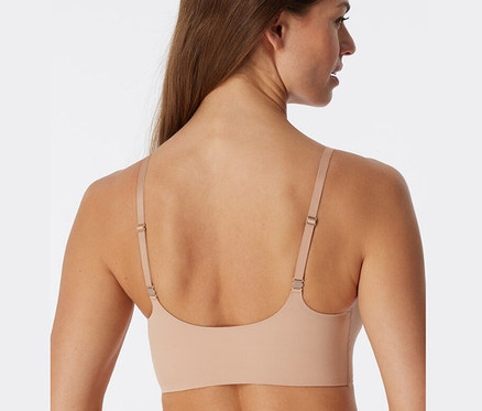 Hátulnézetből látható egy barna hajú nő, aki SCHIESSER láthatatlan, betétes, juharszínű melltartót visel.