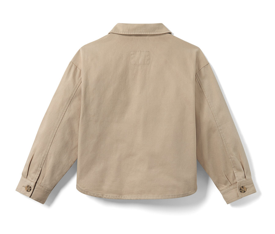 Hátulnézet egy lány bézs színű oversize farmerdzsekiről.