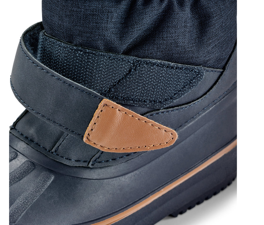 Közelkép egy gyerekcsizma minden időjárásra, kék csizma tépőzárral és barna bőr részlettel.