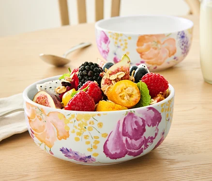 Az asztalon két virágos 2 porcelán tál gyümölccsel, egy üveg tej és egy csésze ital látható.
