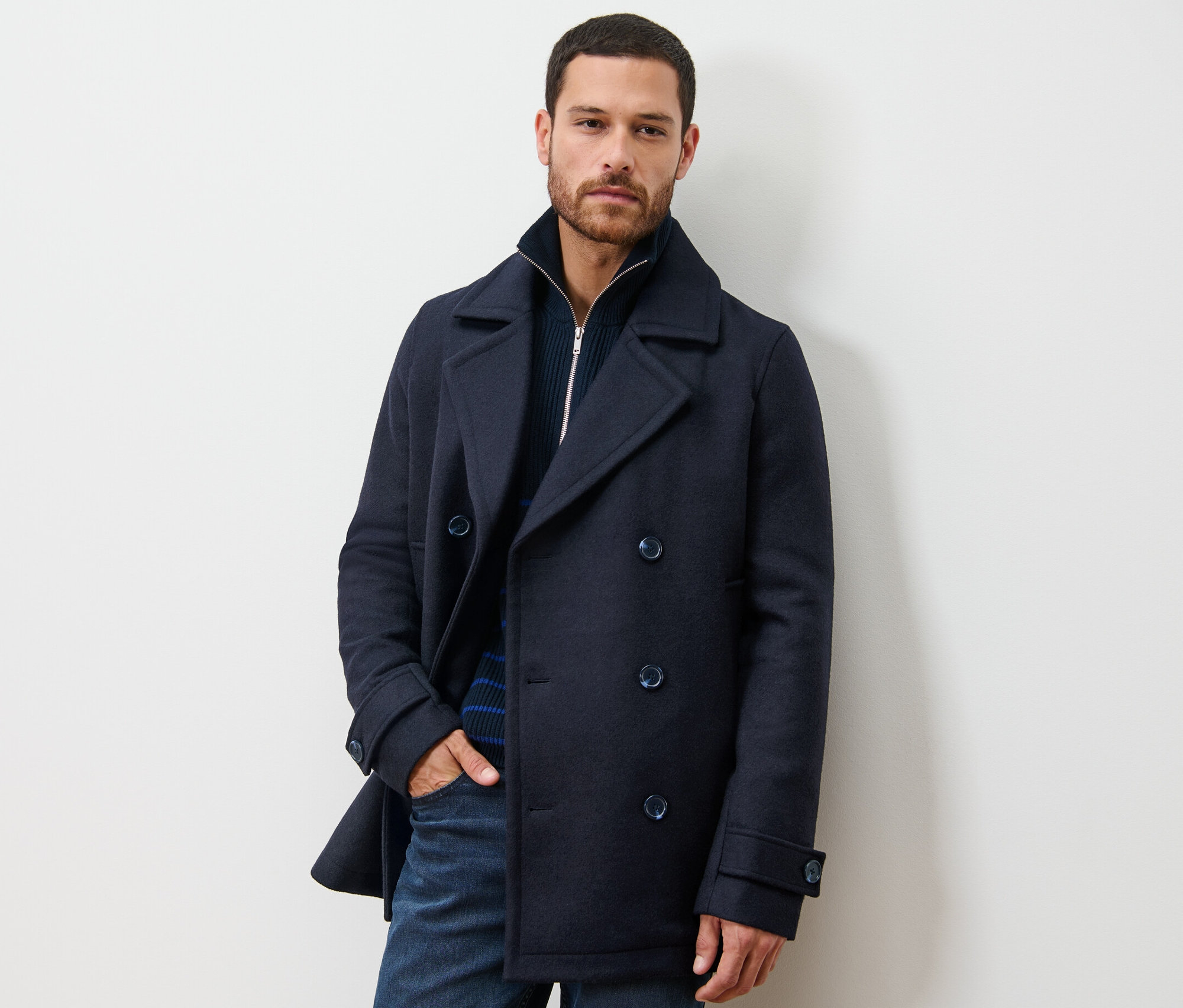 Férfi tengerészkabátban pózol.