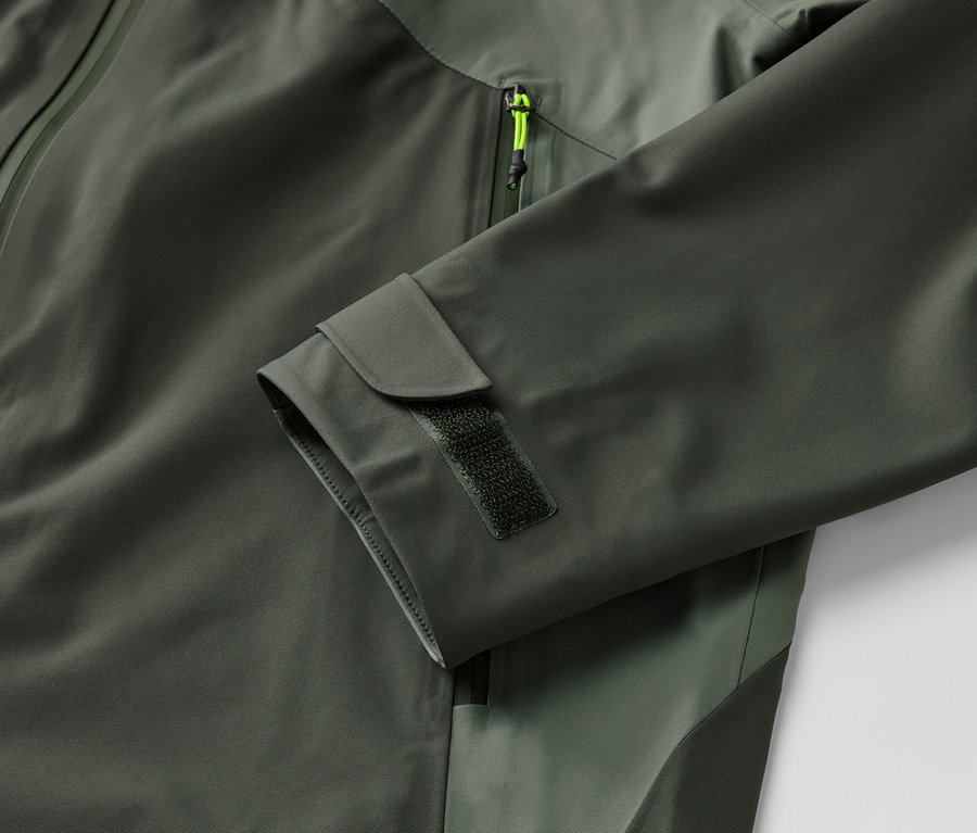 Khaki színű, háromrétegű outdoor dzseki részlete cipzárral és ujjrész szegéllyel.