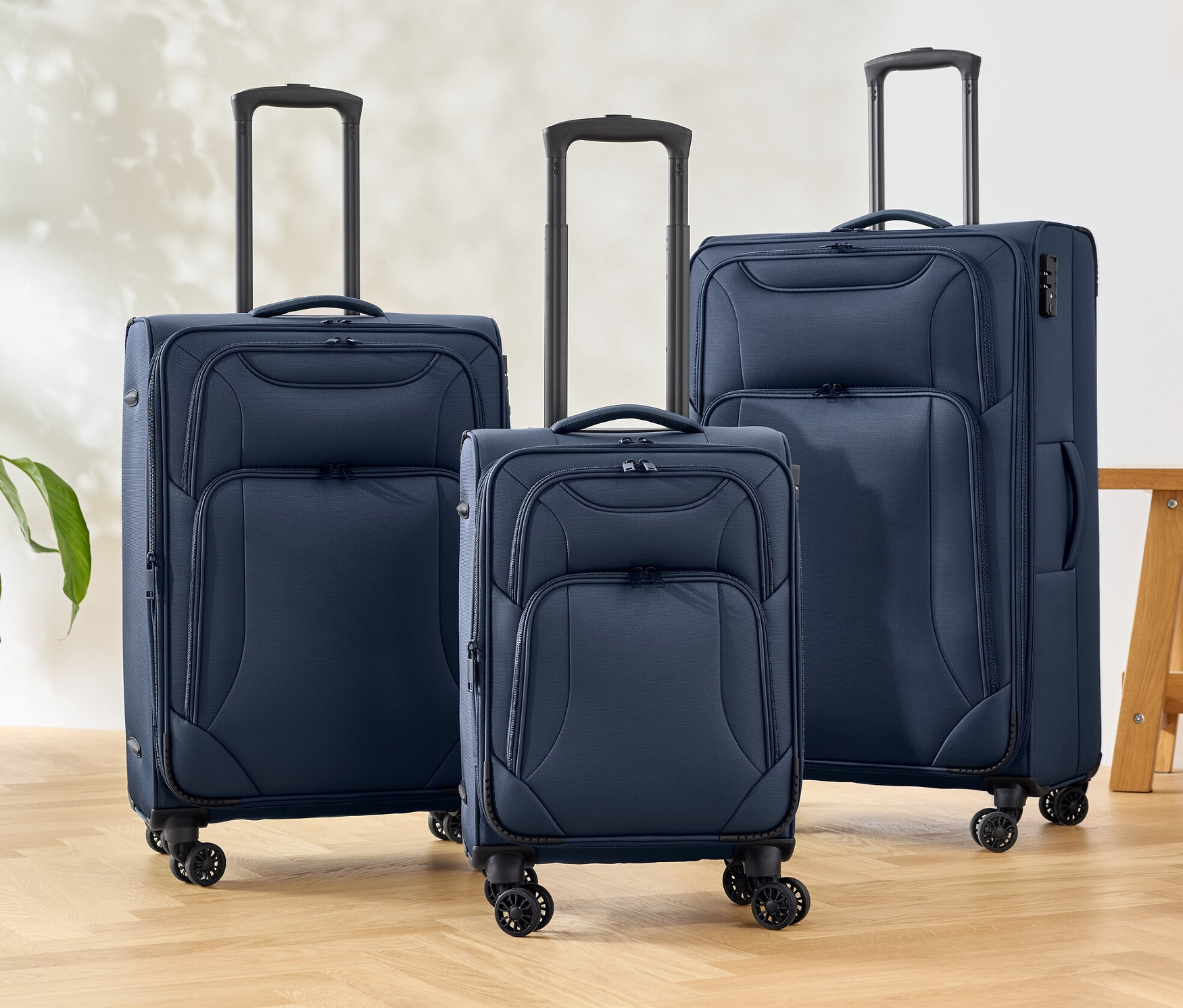 Három kék textilbőrönd áll a padlón.