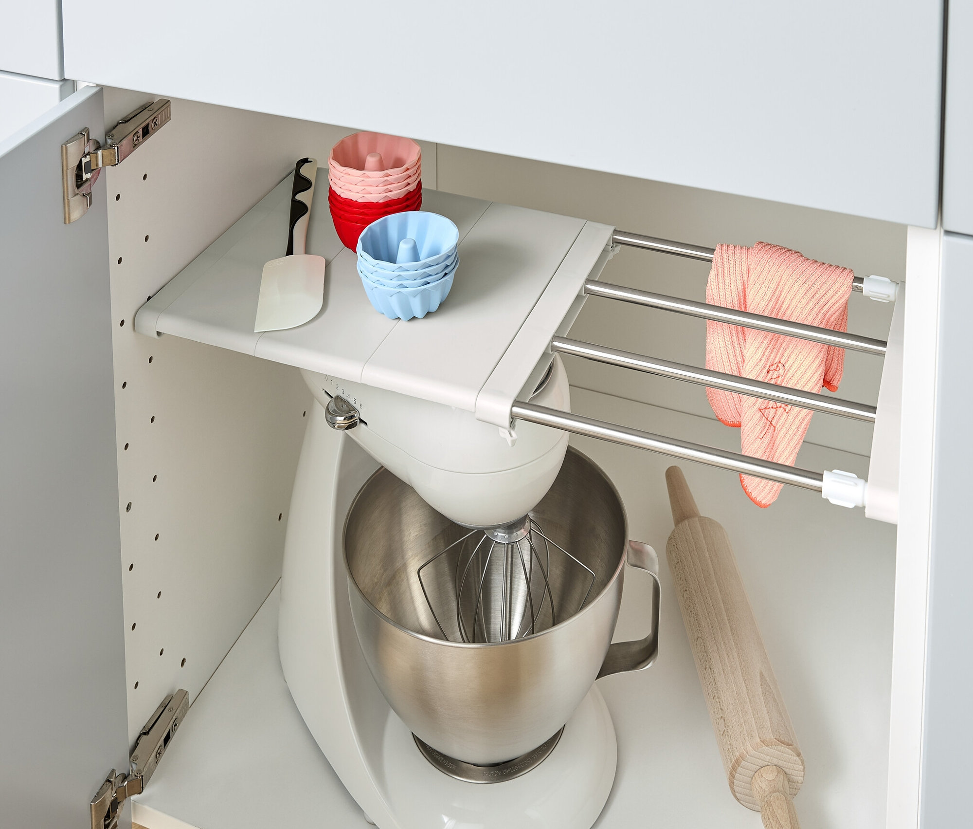 A konyhaszekrényben kihúzható polclap, egy konyhai robotgép, egy sodrófa és szilikonformák találhatók.