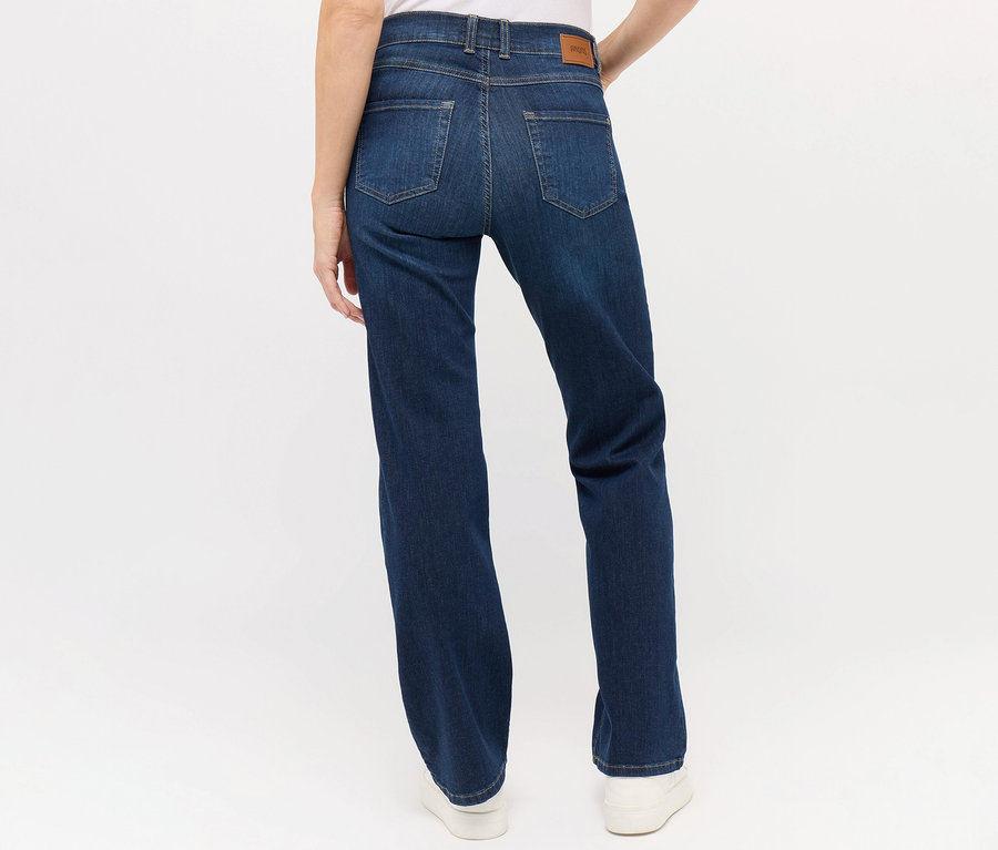 Hátulnézet egy nőről, aki sötétkék Angels »Lara« straight fit farmert és fehér cipőt visel.