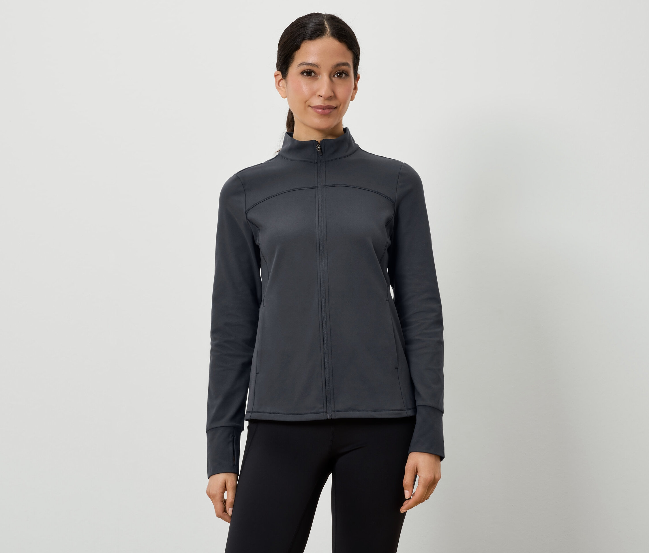 Nő sötétszürke sportkabátot és fekete leggingset visel.