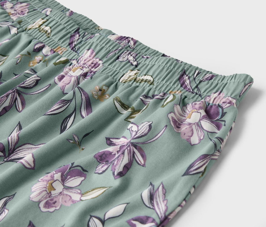Világoszöld nadrág részlete lila virágokkal és gumis derékpánttal.