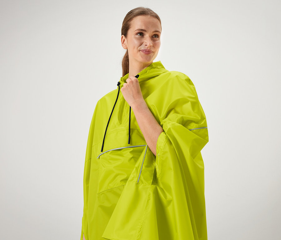 Nő tartja egy neonzöld poncsó gallérját.