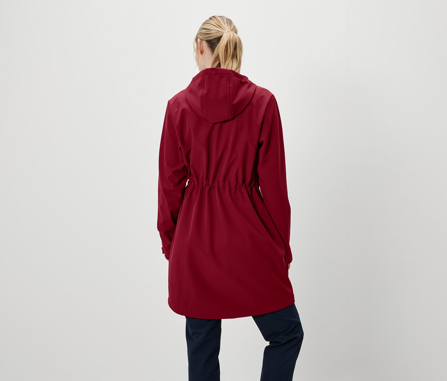 Egy nő hátulról látható, piros kapucnis kabátot és sötétkék nadrágot visel.