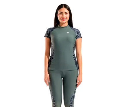 Egy mosolygó nő sötétzöld arena női, UV-védős, mintás, rövid ujjú rashguard úszópólót visel mintás ujjakkal és oldalakkal, hozzá illő leggingsekkel.