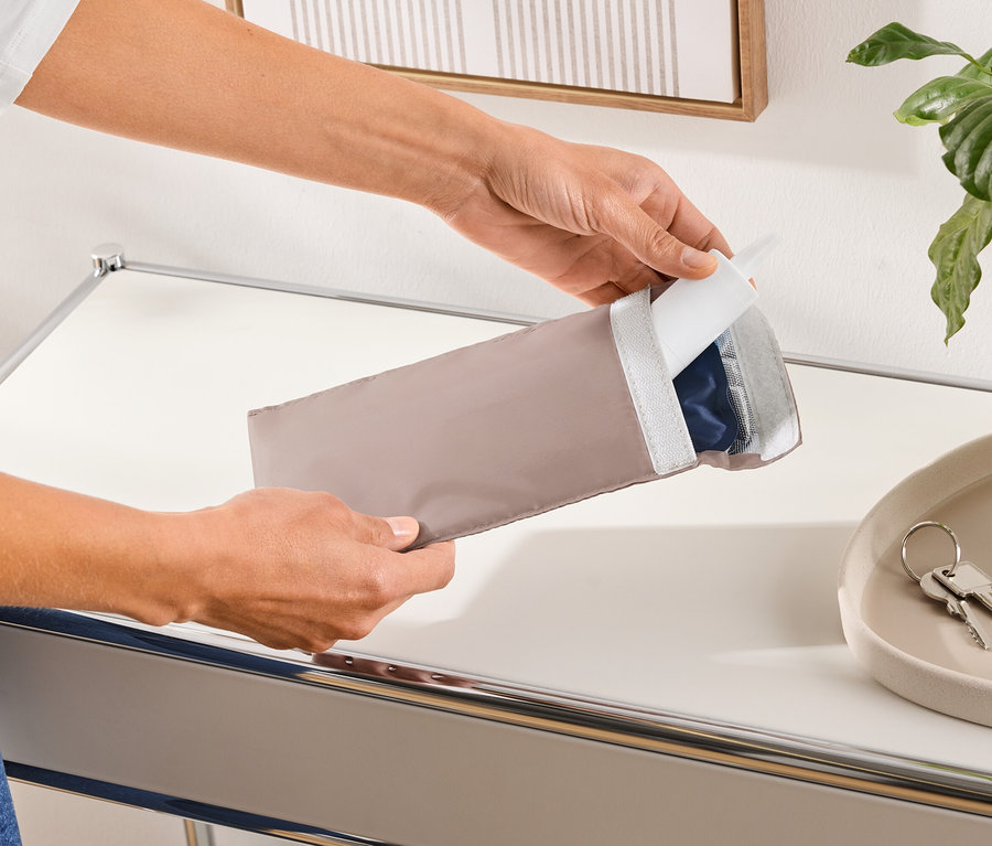 Egy személy egy hosszúkás, bézs színű védőtokot nyit ki, amely egy kék terméket tartalmaz.