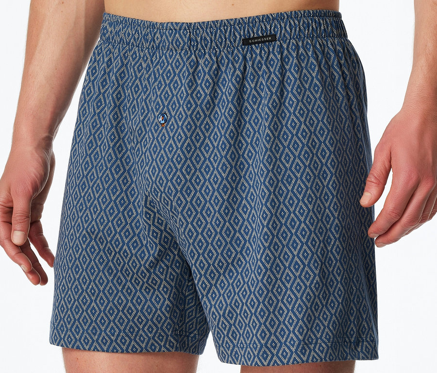 Férfi visel kék SCHIESSER jersey boxeralsót rombuszmintával és gombos záródással.