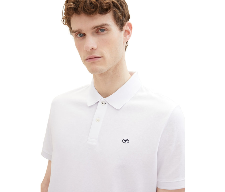 Férfi visel egy fehér Tom Tailor piké pólóinget.