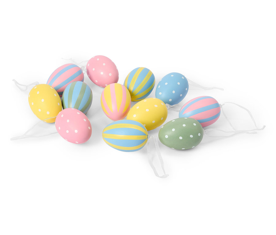 Egy fehér háttéren több pasztell húsvéti tojás fekszik pöttyös és csíkos mintákkal.