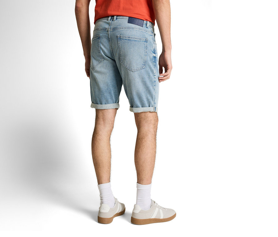 Hátulról látható férfi Tom Tailor TTJOSH REGULAR SLIM farmer rövidnadrágban, kőmosott világoskék denimben, fehér zokniban és tornacipőben.