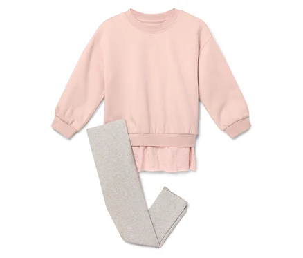 Egy rózsaszín pulóver szürke leggings mellett fekszik.