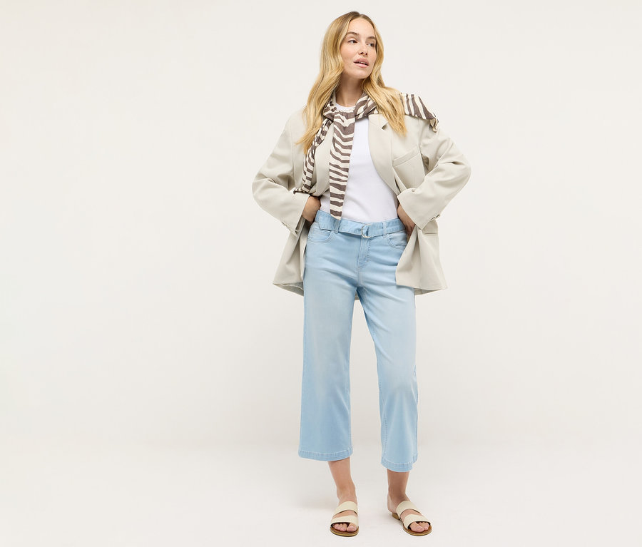 Egy nő áll, és Angels denim »Linn City« bokát szabadon hagyó farmernadrágot, fehér pólót, blézert és sálat visel.