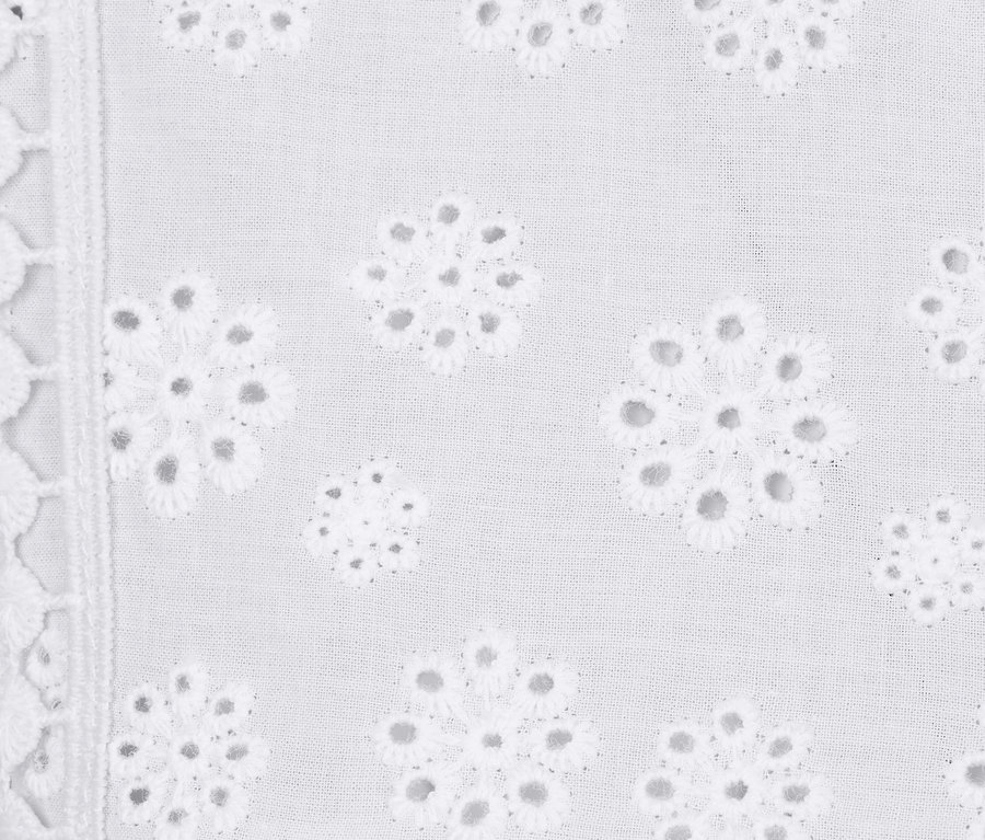Egy fehér, hímzett női top részletgazdag képe.