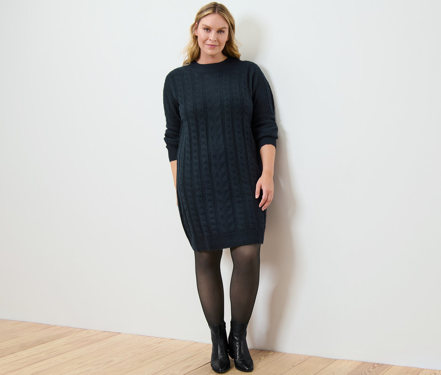 Nő pózol kötött ruhában és fekete, átlátszó hatású 50 DEN harisnyában.