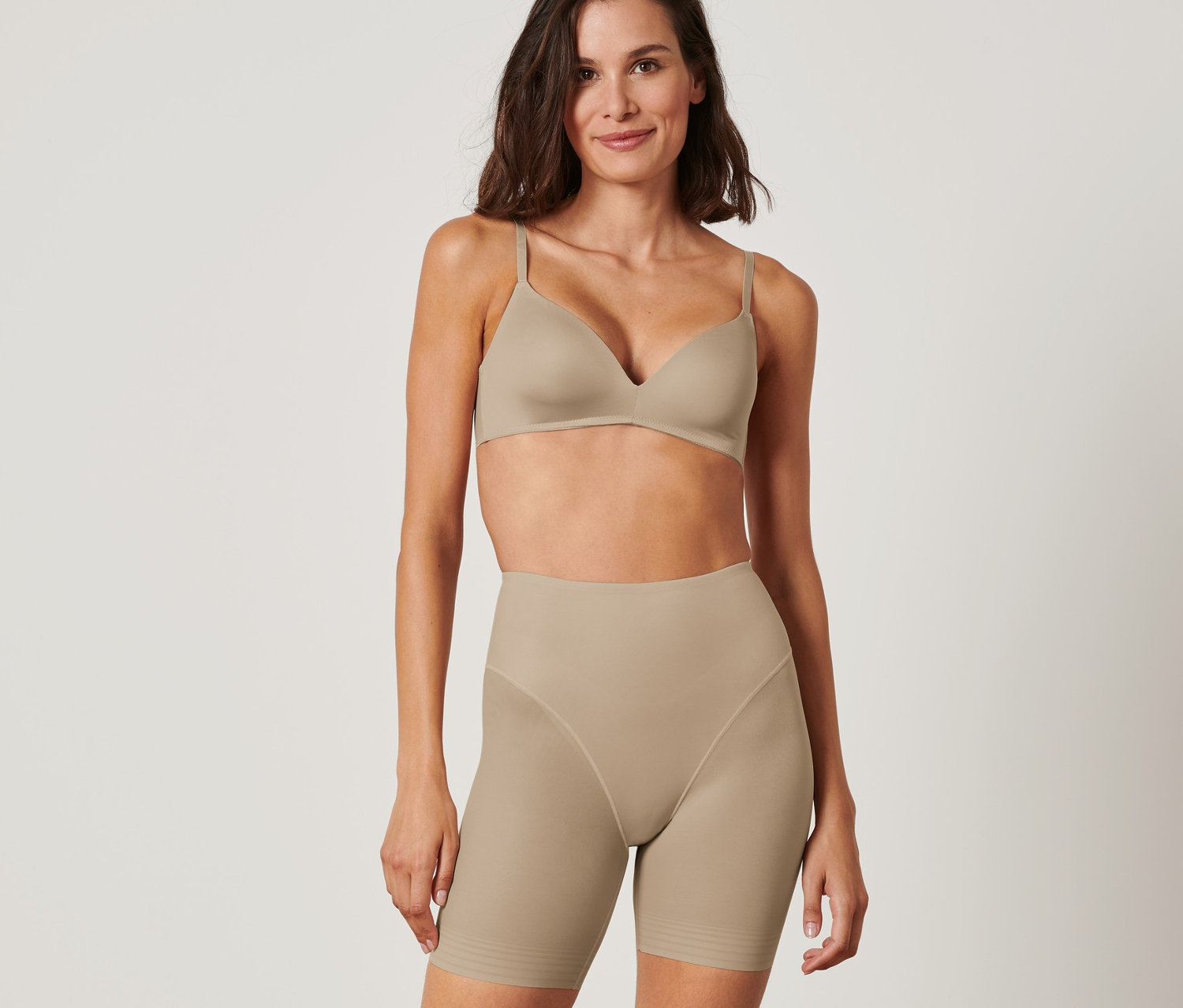 Nő alakformáló rövidnadrágban és melltartóban pózol.