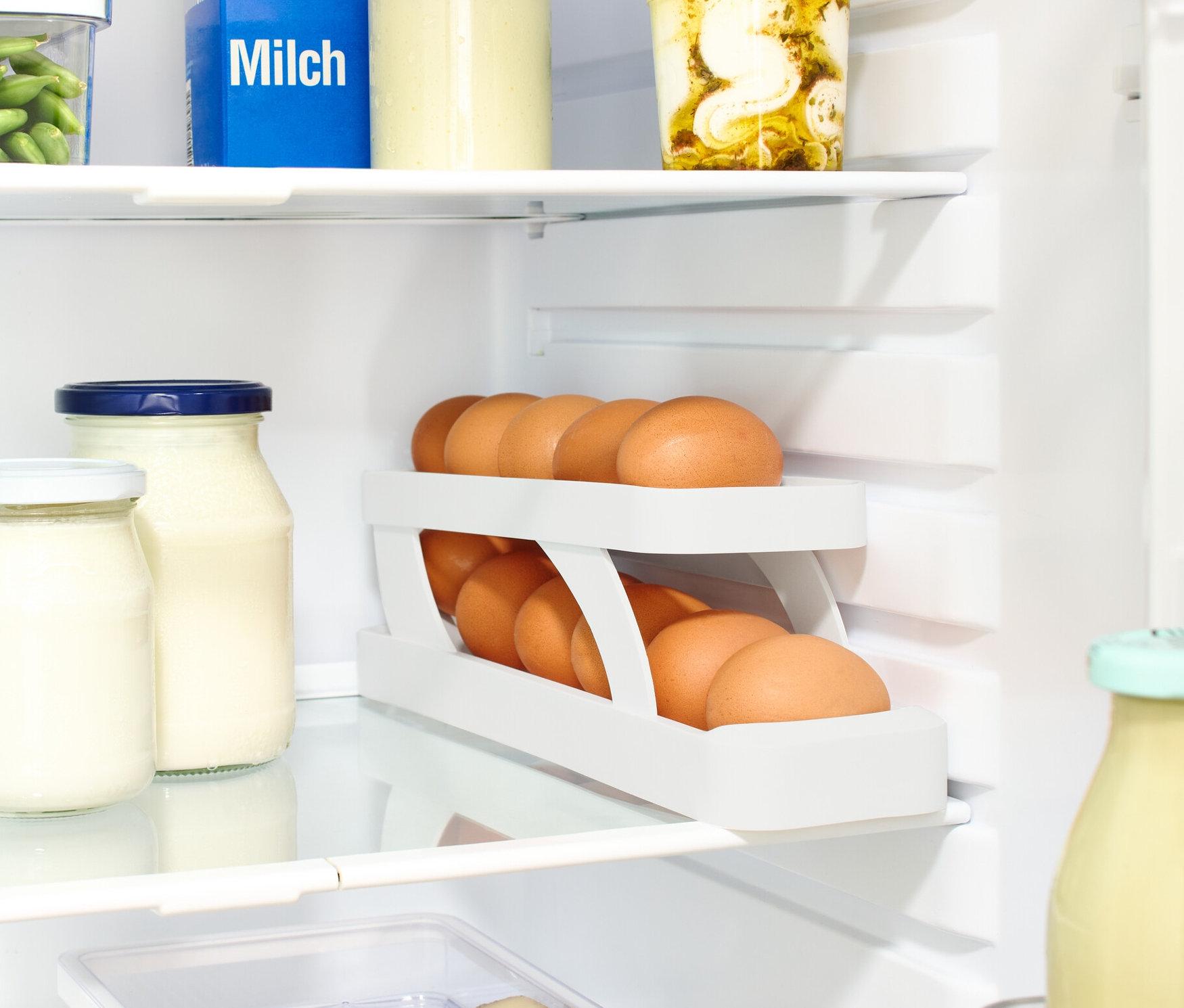 A hűtőszekrényben tej, üvegek és egy Tojástartó található.