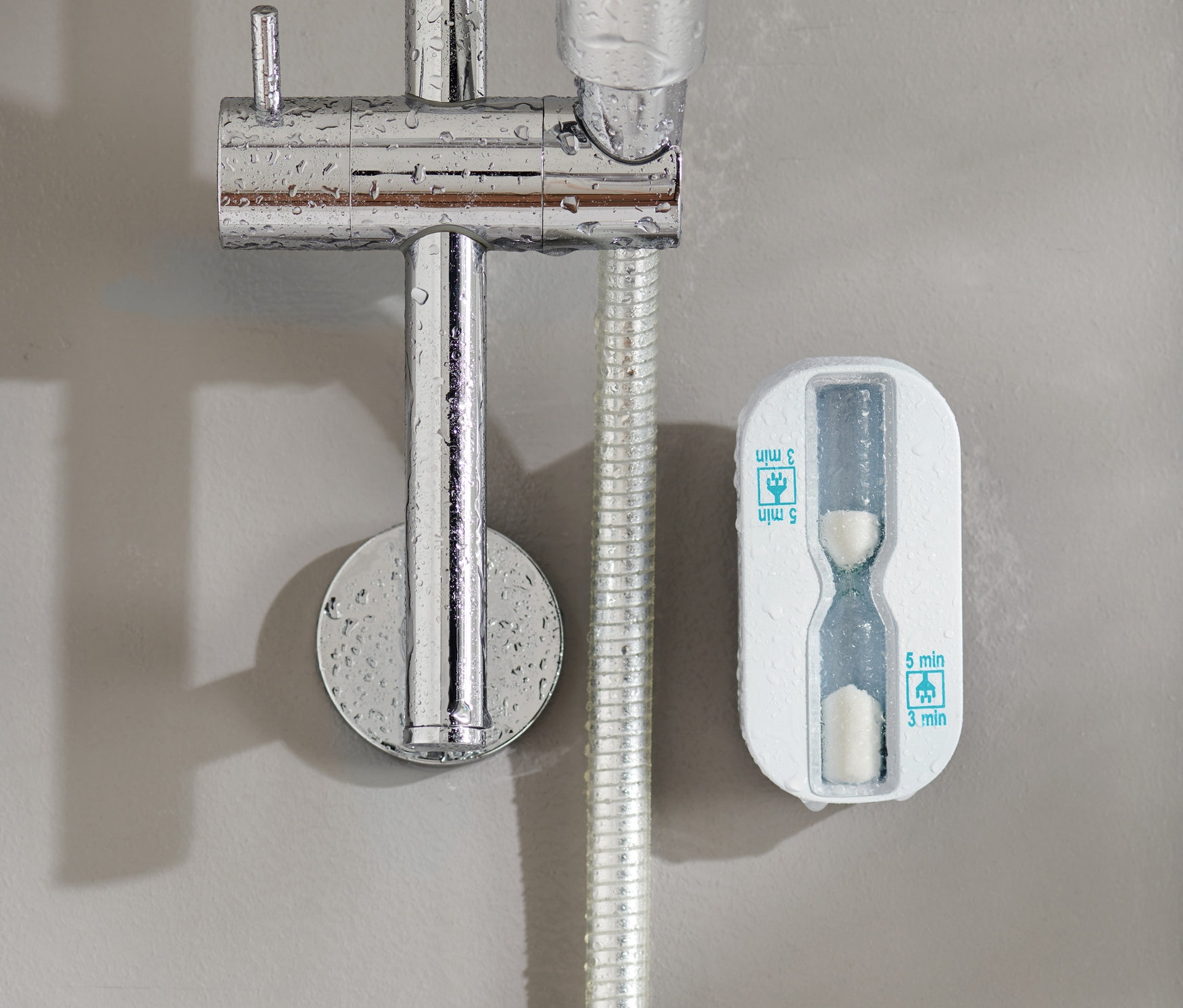 Zuhanyzó homokóra a falra szerelve a zuhanyfej mellett.