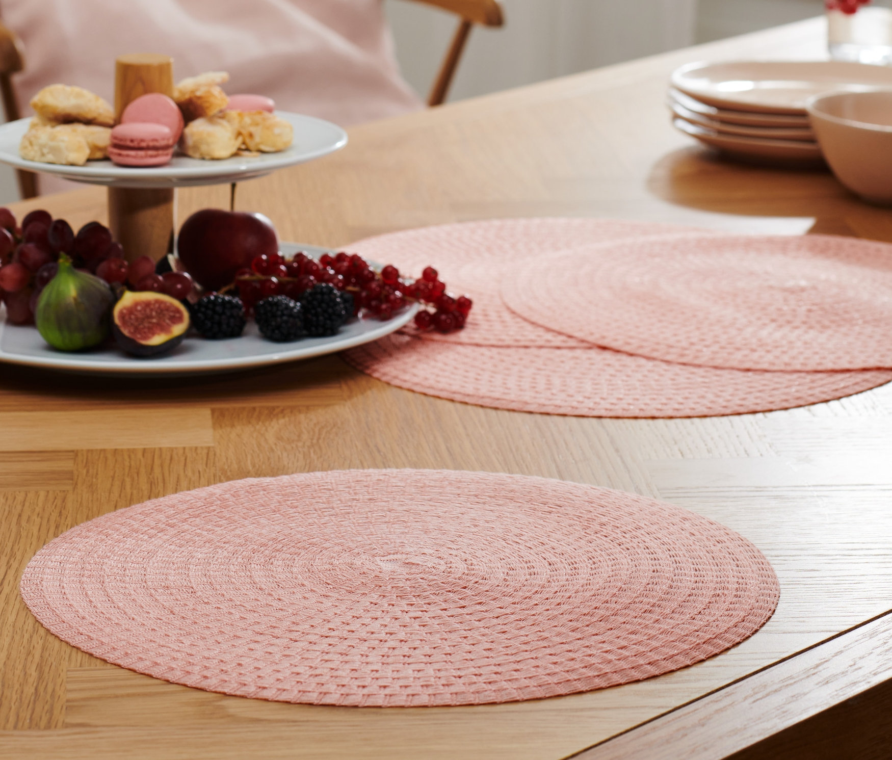 Egy asztalon 4 rózsaszín, kerek tányéralátét látható.