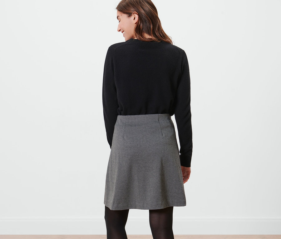 Nő visel fekete pulóvert és női lezser szoknyát.