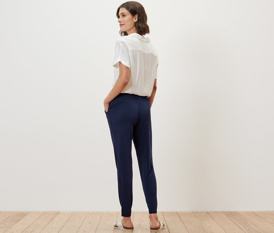 A nő háttal áll a kamerának, sötétkék jersey nadrágot visel.