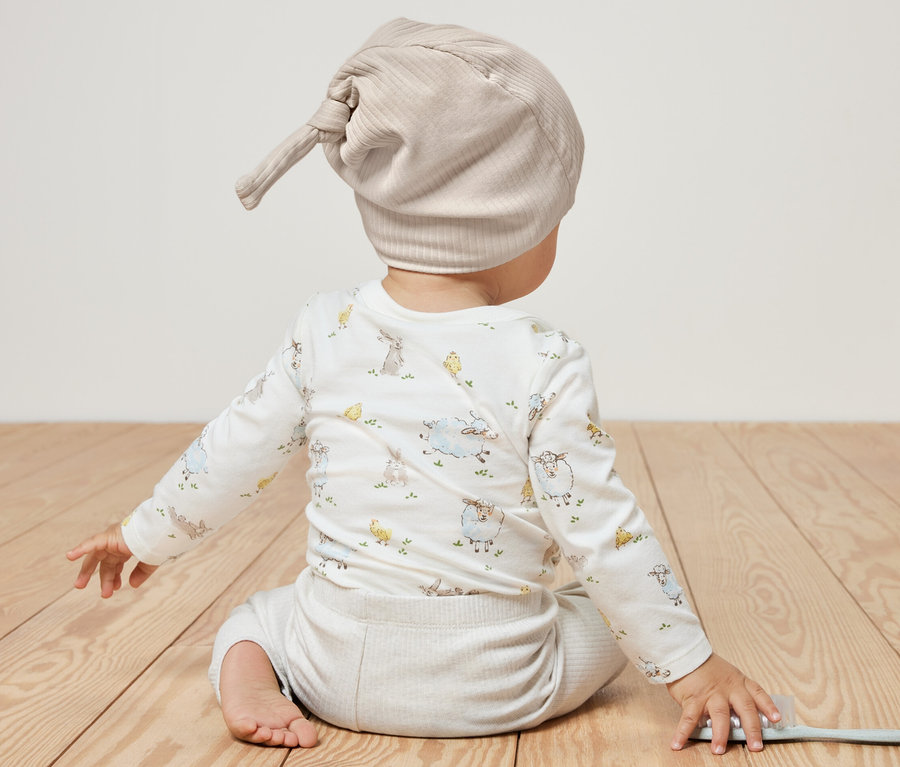 A baba háttal ül a kamerának, és 2 kisgyerek sapka van rajta, világoskék/bézs.