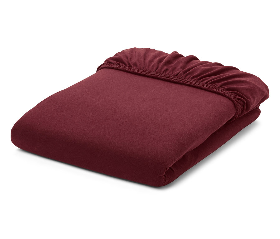 Összehajtott, bordó színű gumis lepedő fehér háttérrel.