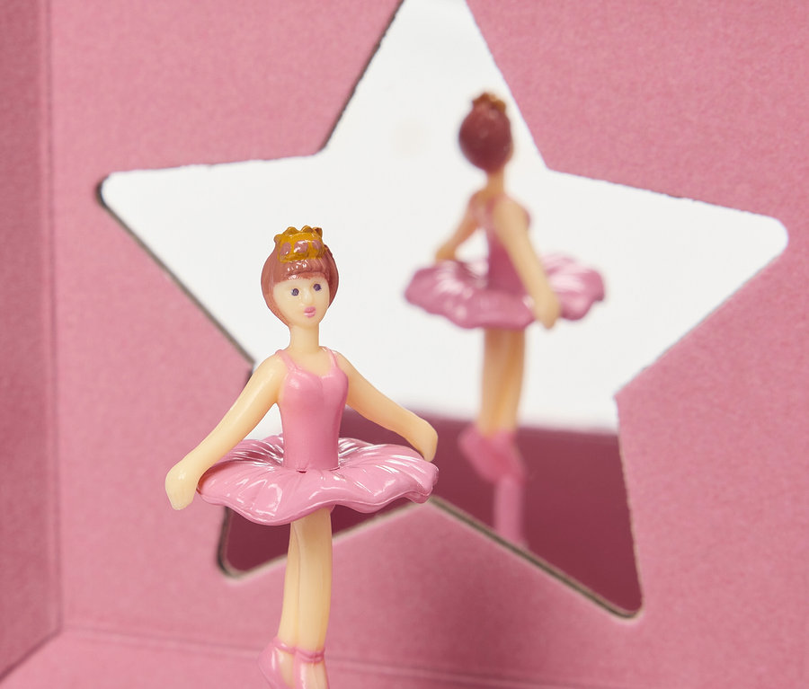 Egy rózsaszín balerina figura koronával egy csillag alakú tükör előtt áll.