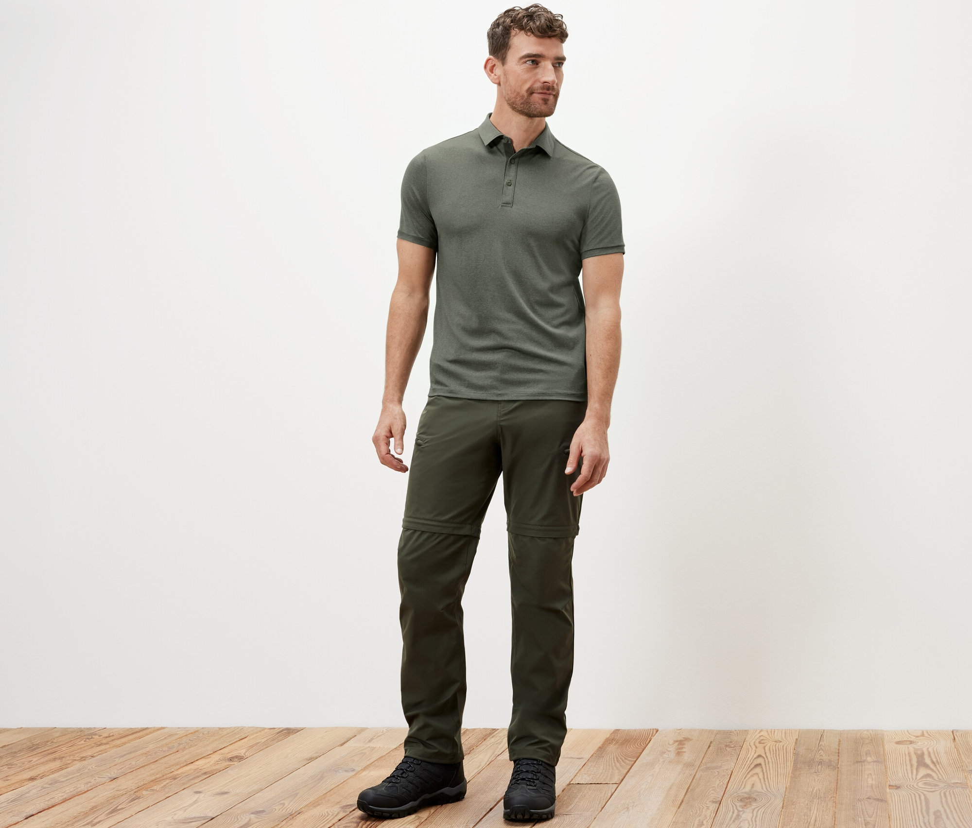 Egy férfi áll khaki színű funkcionális pólóingben.