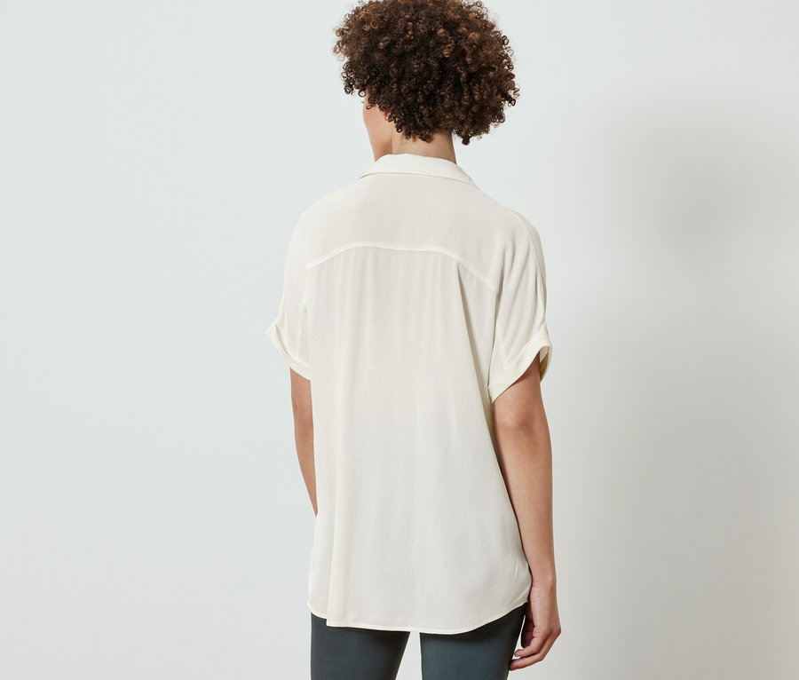 Hátulnézet egy nőről, aki krémszínű blúzt visel.