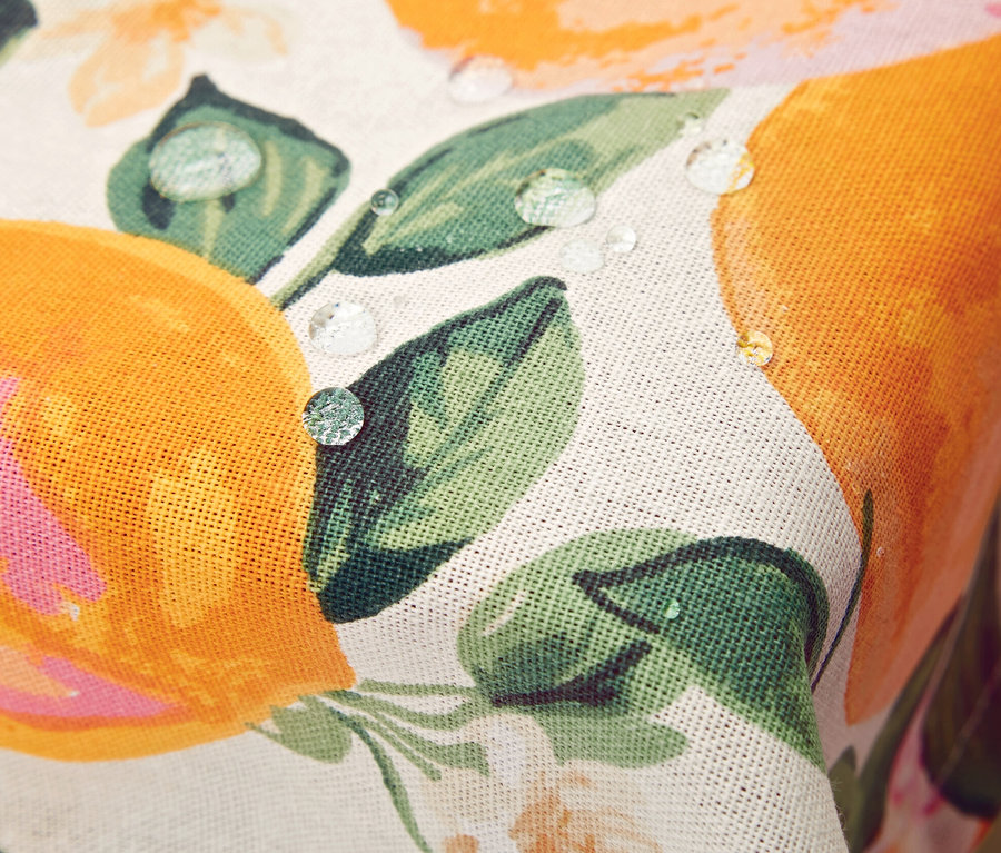 Egy narancs és virág mintás, letörölhető asztalterítő részlete, melyen vízcseppek láthatók.