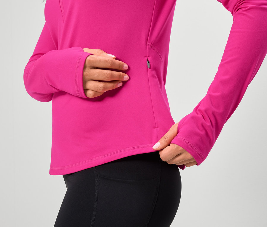 Nő visel rózsaszín, hosszú ujjú felsőt és fekete leggingset.