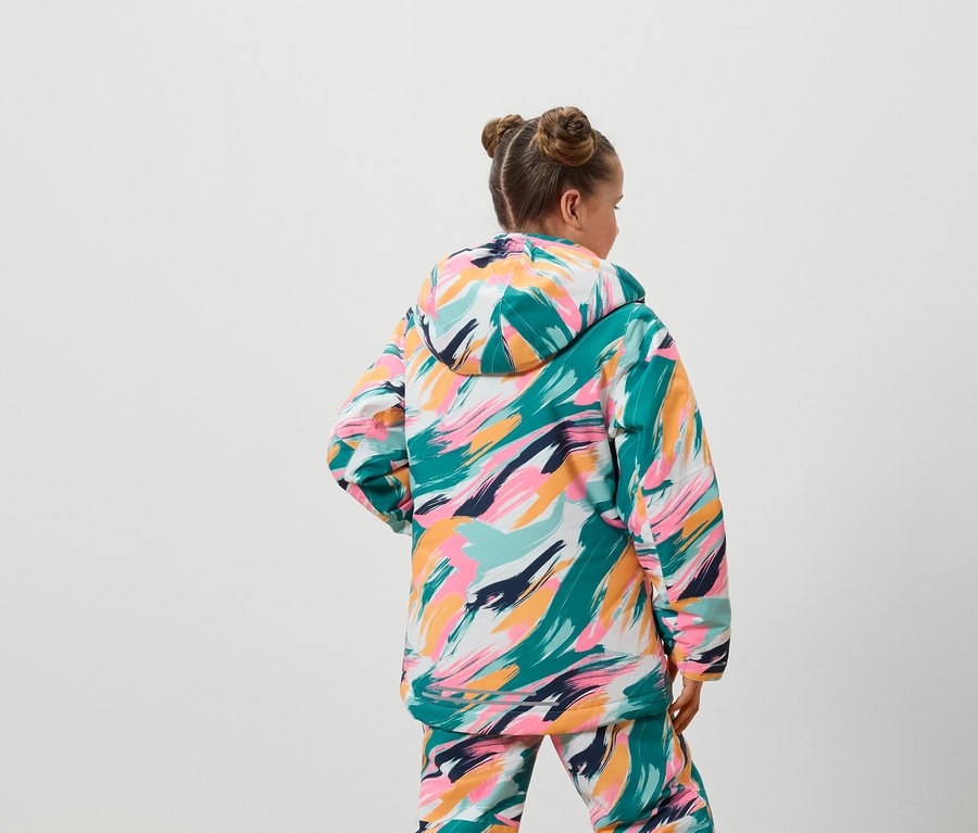 Hátulról látható egy lány színes kabátban és nadrágban.