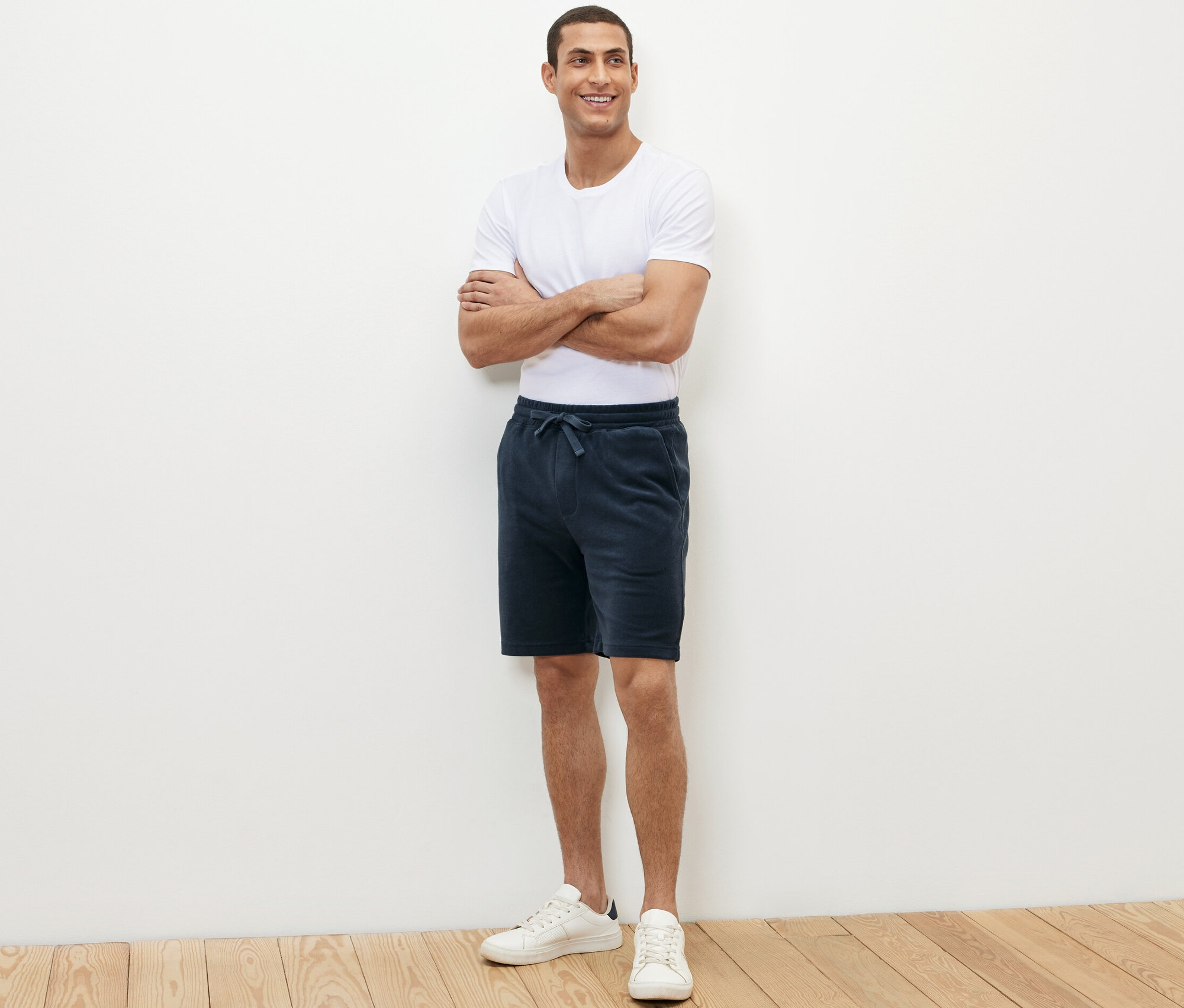 Férfi áll keresztbe font karokkal, kék frottír rövidnadrágot visel.