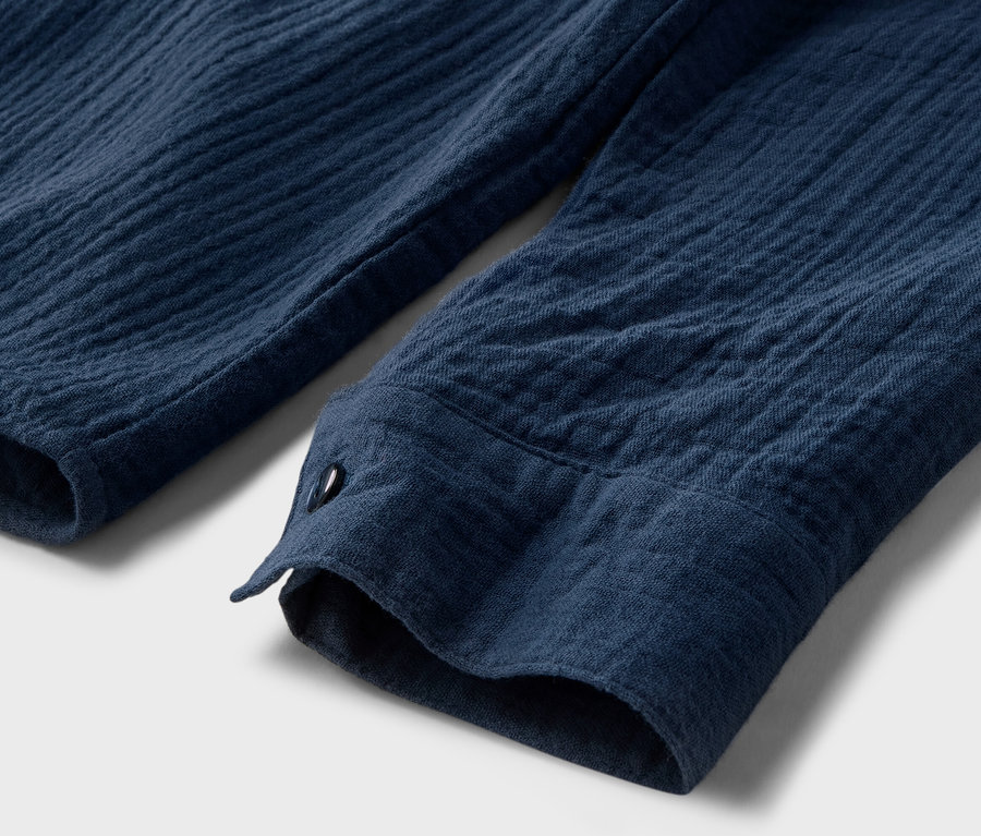 Egy sötétkék muszlin blúz részletfotója gombbal.